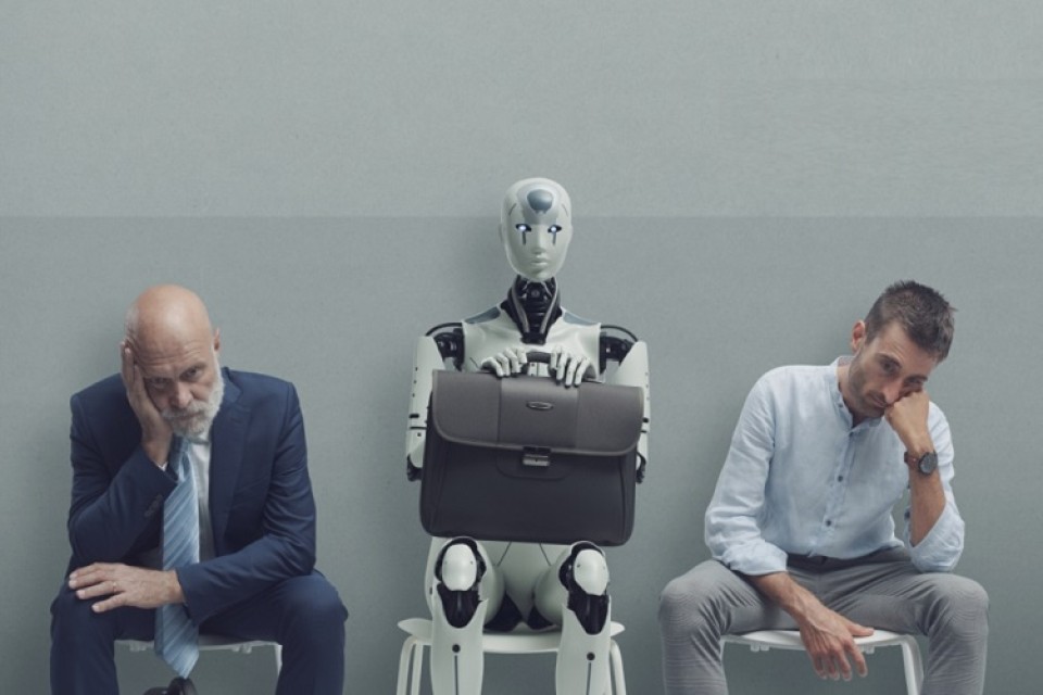 Twee mannen zitten te sippen naast robot|Robot en man in pak kijken elkaar aan|Man en vrouwen kijken robot aan.