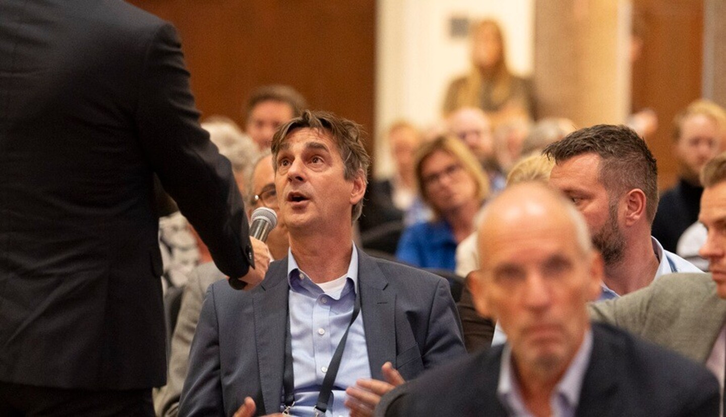 Deelnemer in de zaal geeft antwoord via microfoon