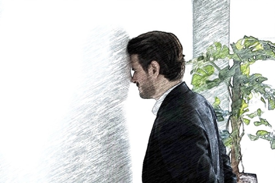 Man staat met hoofd tegen de muur