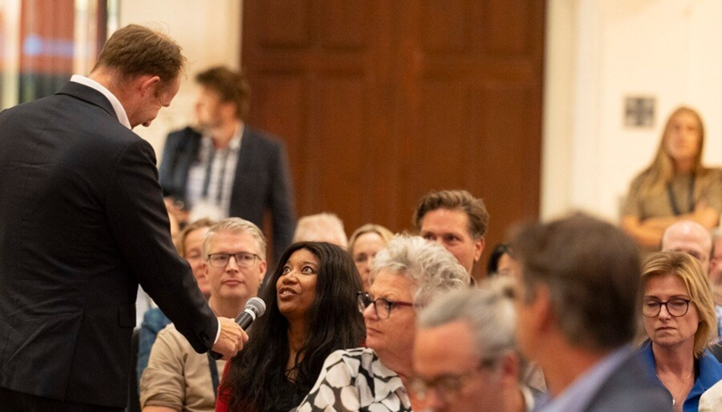 Een vrouw in de zaal geeft antwoord via de microfoon