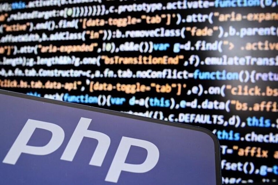 Blauw bordje met de witte letters php, voor een scherm met gekleurde programmeercode.