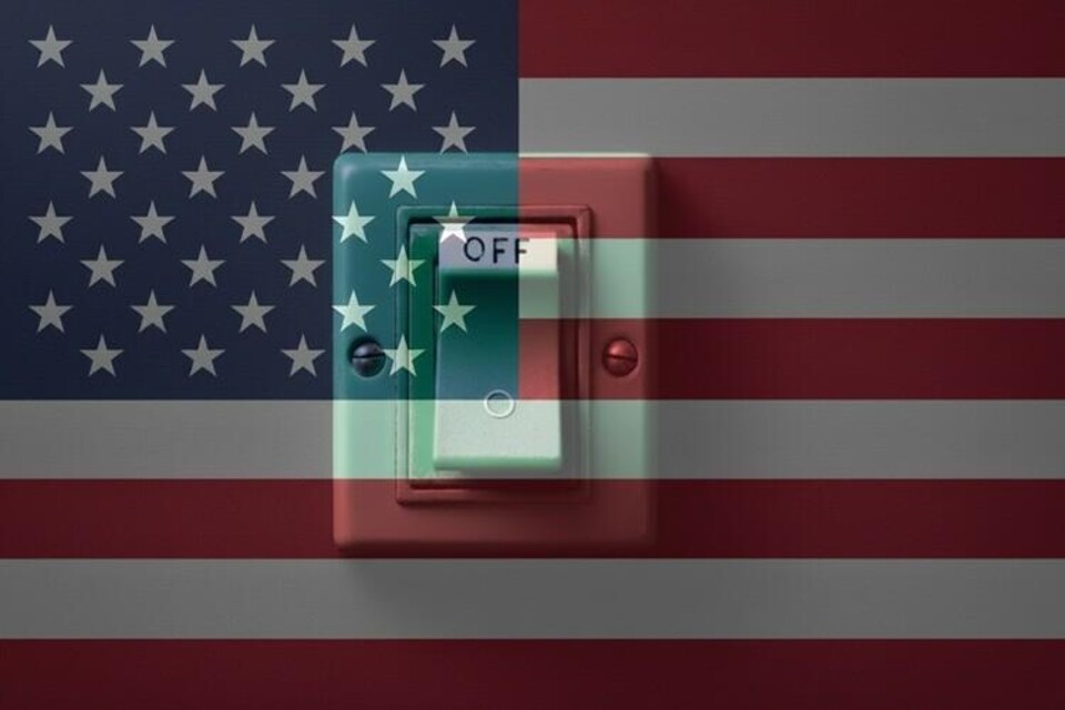 Een lichtschakelaar met de tekst 'OFF' voor een vervaagde Amerikaanse vlag op de achtergrond.