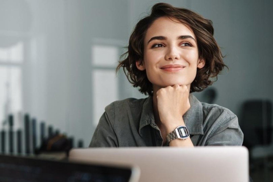 vrouw kijkt blij boven haar laptop