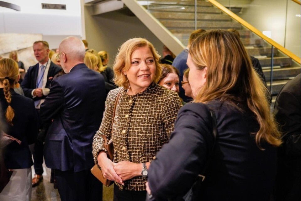 Henna Virrkunen praat met een andere vrouw in een hal, met andere mensen op de achtergrond