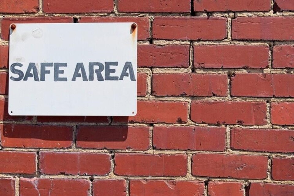 muur van baksteen met daarop een bord 'safe area'