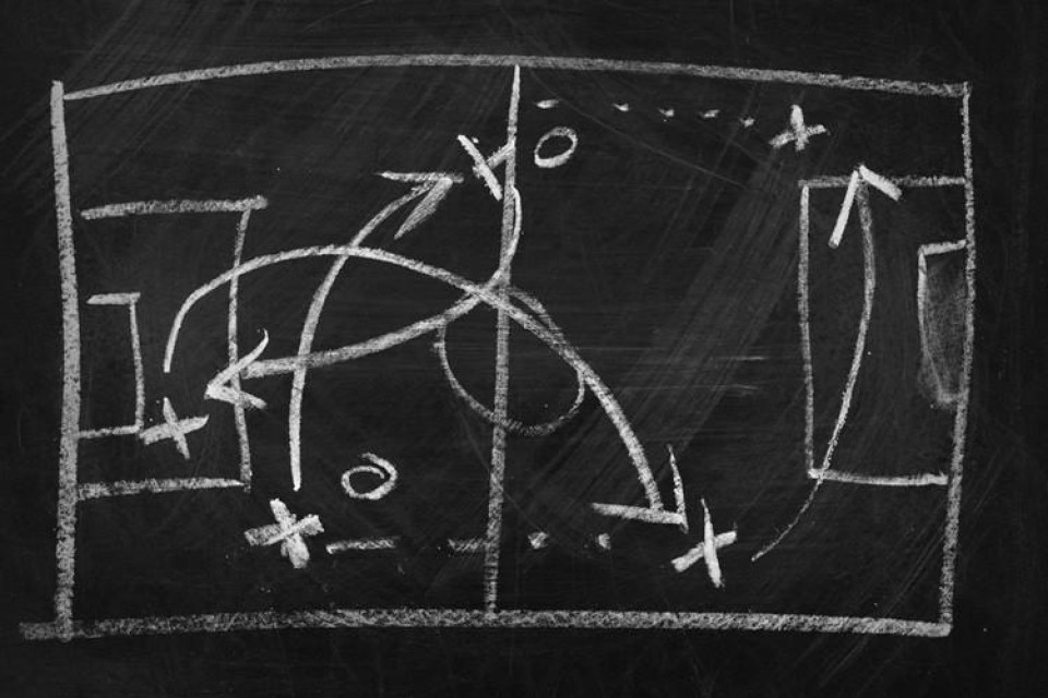 Schoolbord waarop voetbalveld getekend met aanvalsplan