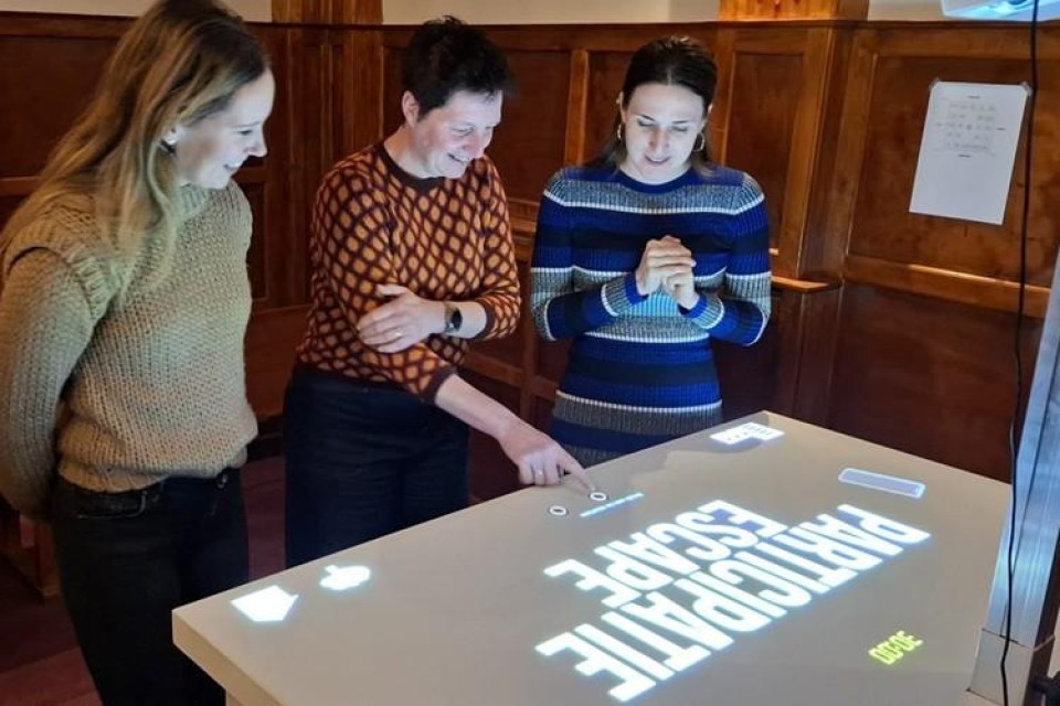 Drie vrouwen achter een tafelscherm waar ze starten met de escaperoom