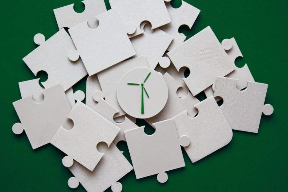Op groene achtergrond liggen witte puzzelstukken met in het midden een tekening van een windmolen