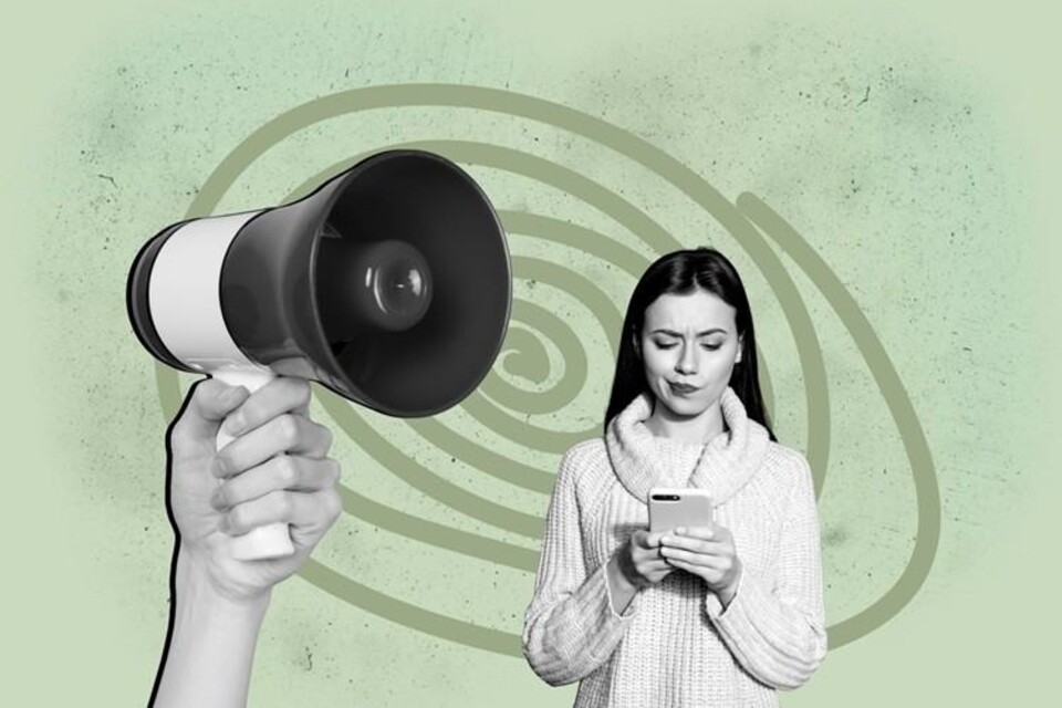 vrouw kijkt op telefoon, naast haar hoofd een megafoon