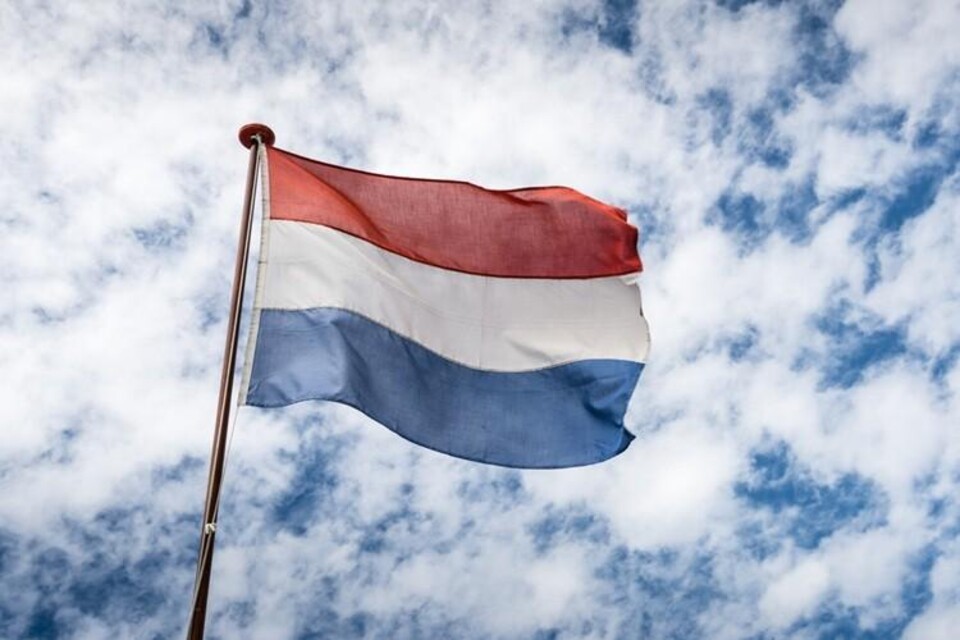 Wapperende Nederlandse vlag tegen bewolkte lucht