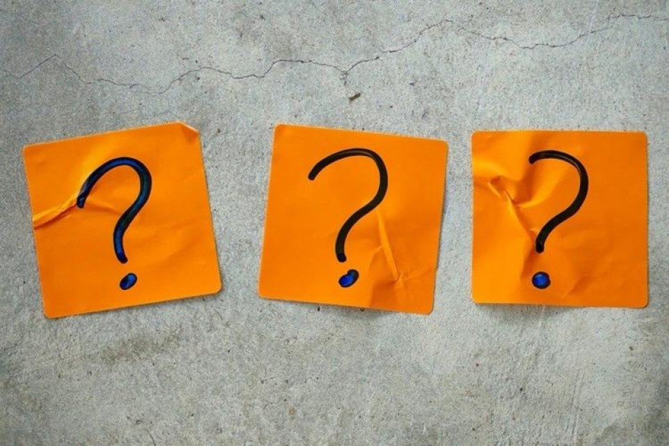 3 vraagtekens op oranje papiertjes tegen grijze achtergrond
