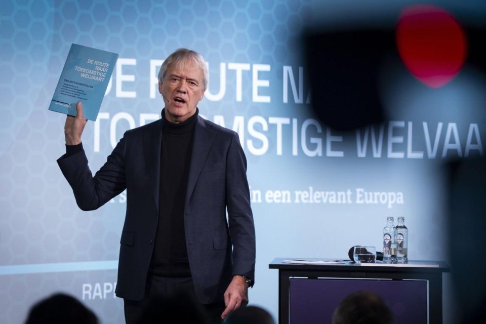 Peter Wennink houdt zijn rapport omhoog tijdens de presentatie