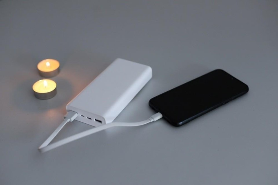 Mobiele telefoon wordt opgeladen, twee brandende waxinelichtjes ernaast