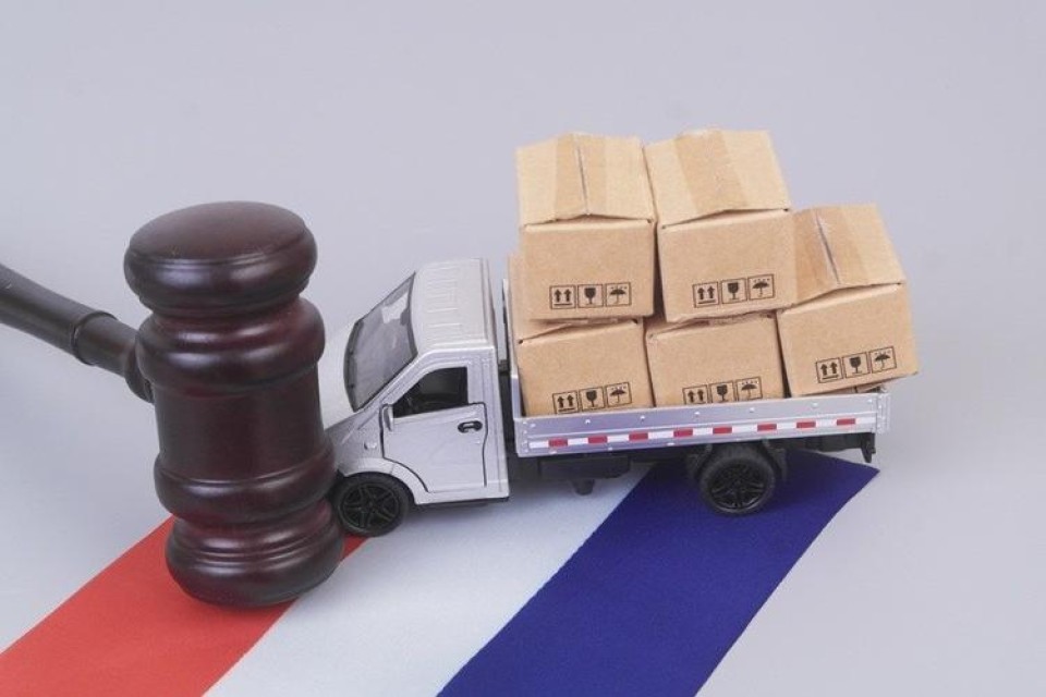 Houten hamer voor een vrachtautootje met lading om een Nederlandse vlag