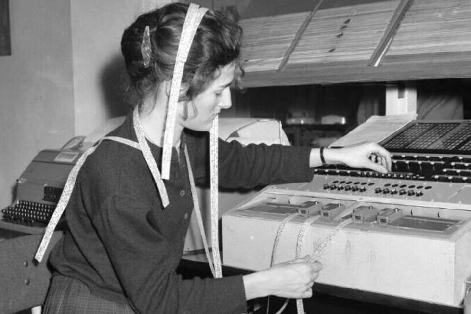 Zwart wit foto van vrouw die telegraaf bedient, lint loopt over haar hoofd