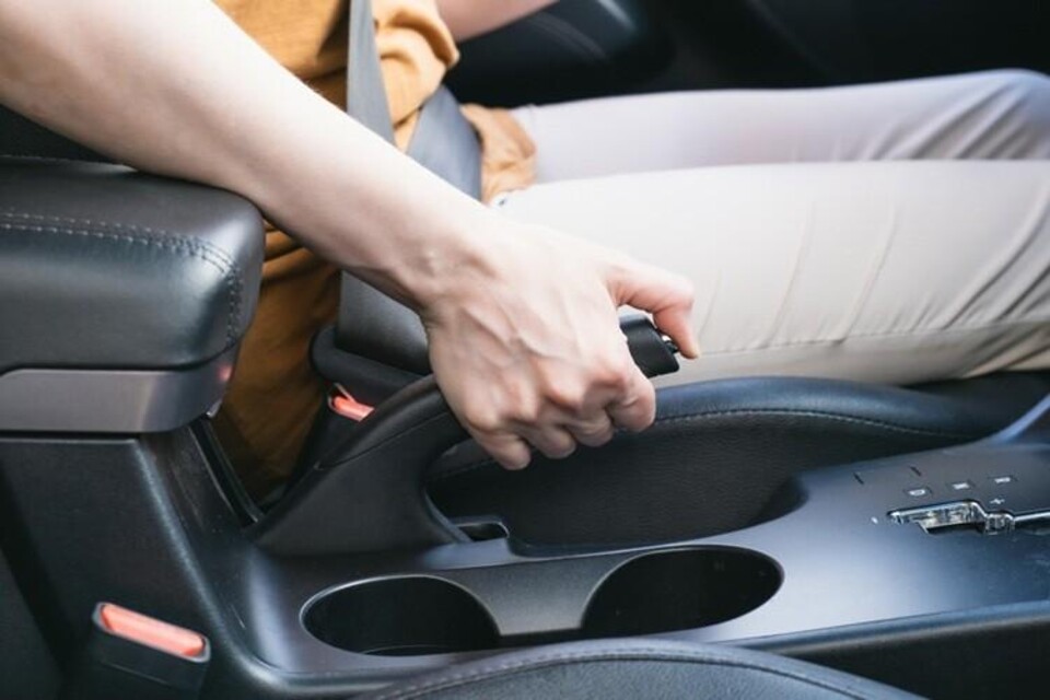 Hand trekt handrem in auto aan
