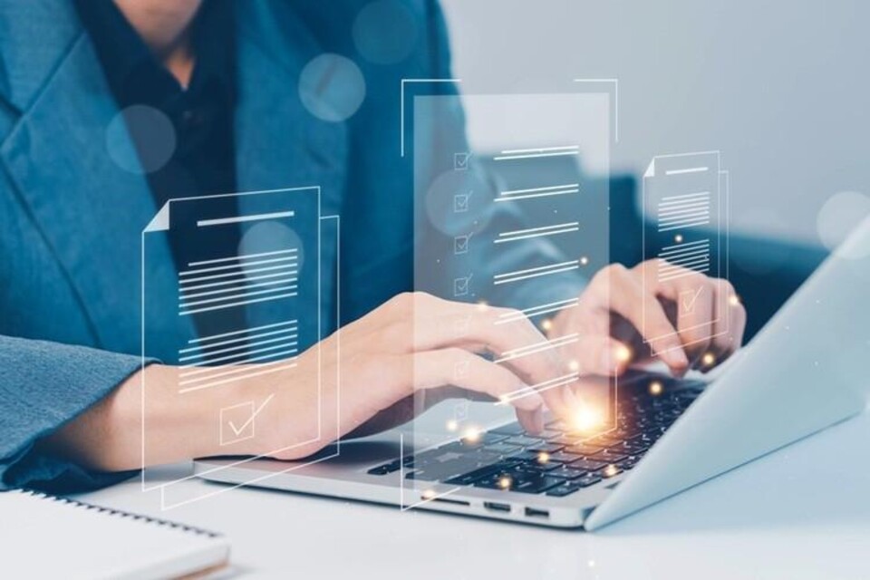 Man vult achter laptop online formulier in