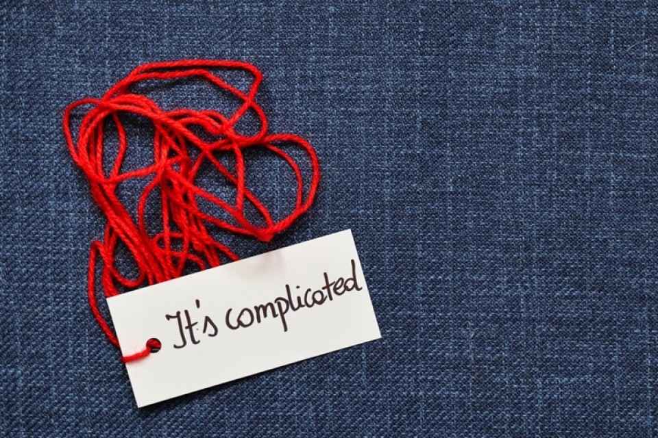 Blauwe achtergrond met rood kluwen garen. Kaartje eraan met tekst 'It's complicated'