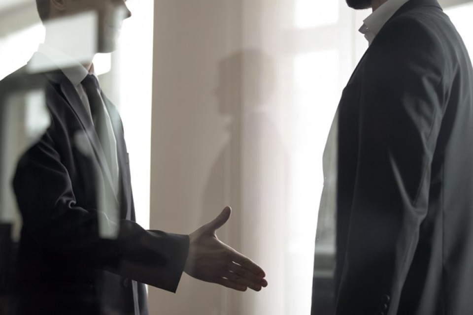 Twee mannen geven elkaar een hand, schimmig beeld|Portret Serv Wiemers